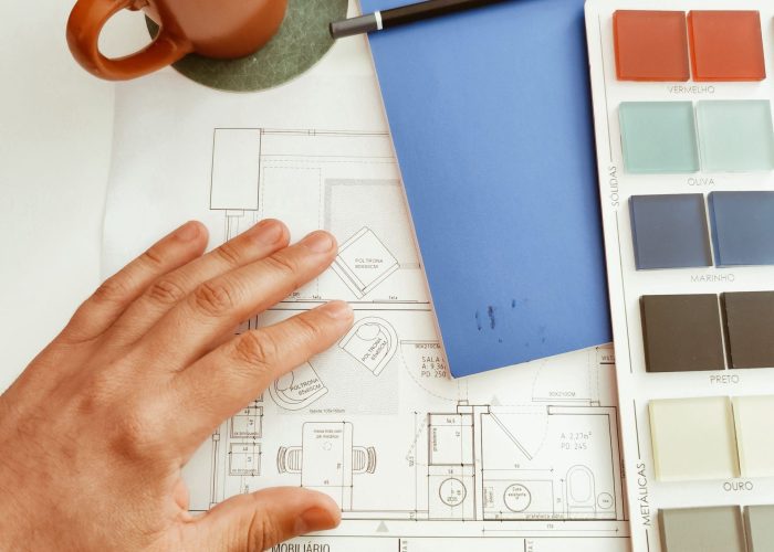 A workspace featuring a coffee cup, color palette, and architectural plans, perfect for design projects.